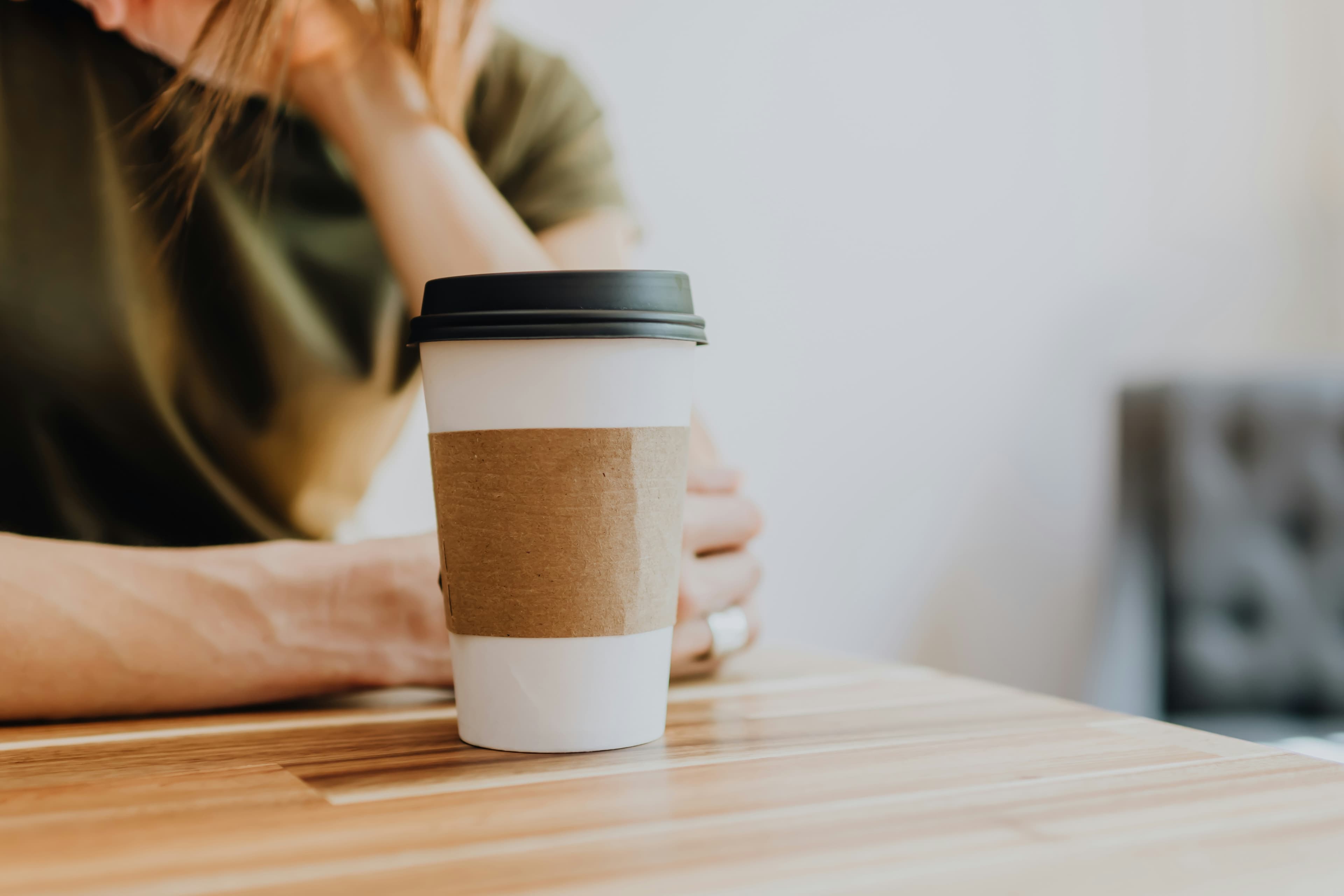 To-go cup with sleeve held by person at a table